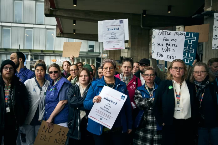 Sineva Ribeiro framför medlemmar med plakat och press utanför Karolinska sjukhuset i Huddinge i samband med att övertidsblockaden startade 25 april 2024, kl 16. konflikt, HÖK 2024